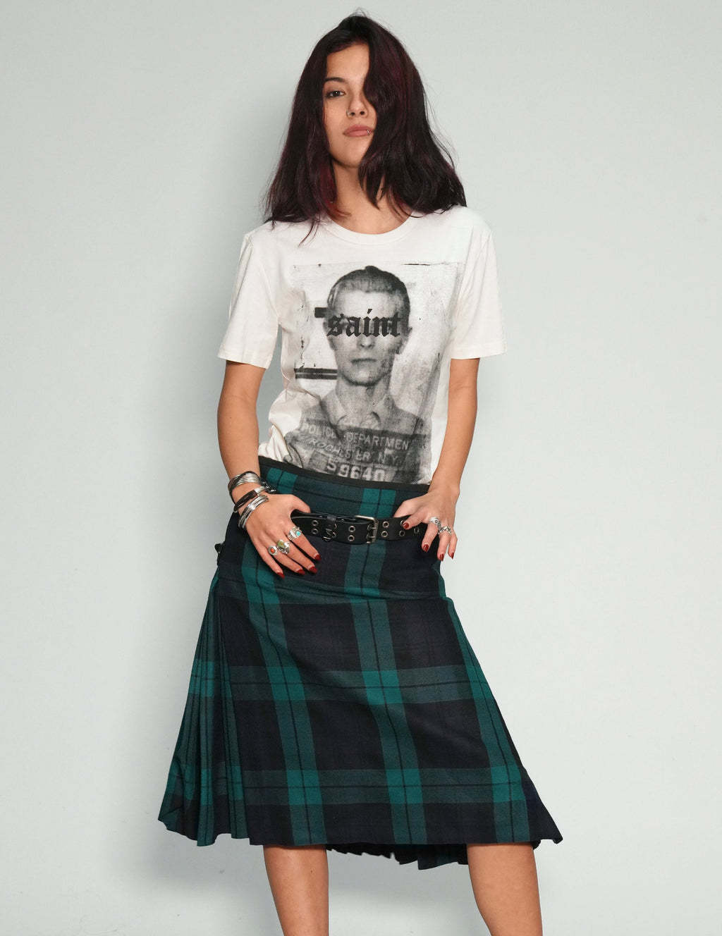 Woman wearing a graphic t-shirt and plaid skirt on a plain background