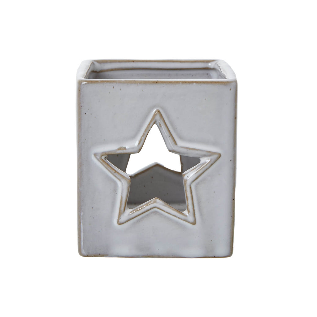 White ceramic tealight holder with star cut-outs, casting delicate light patterns, minimalist home decor. by sostter at brixbailey.com