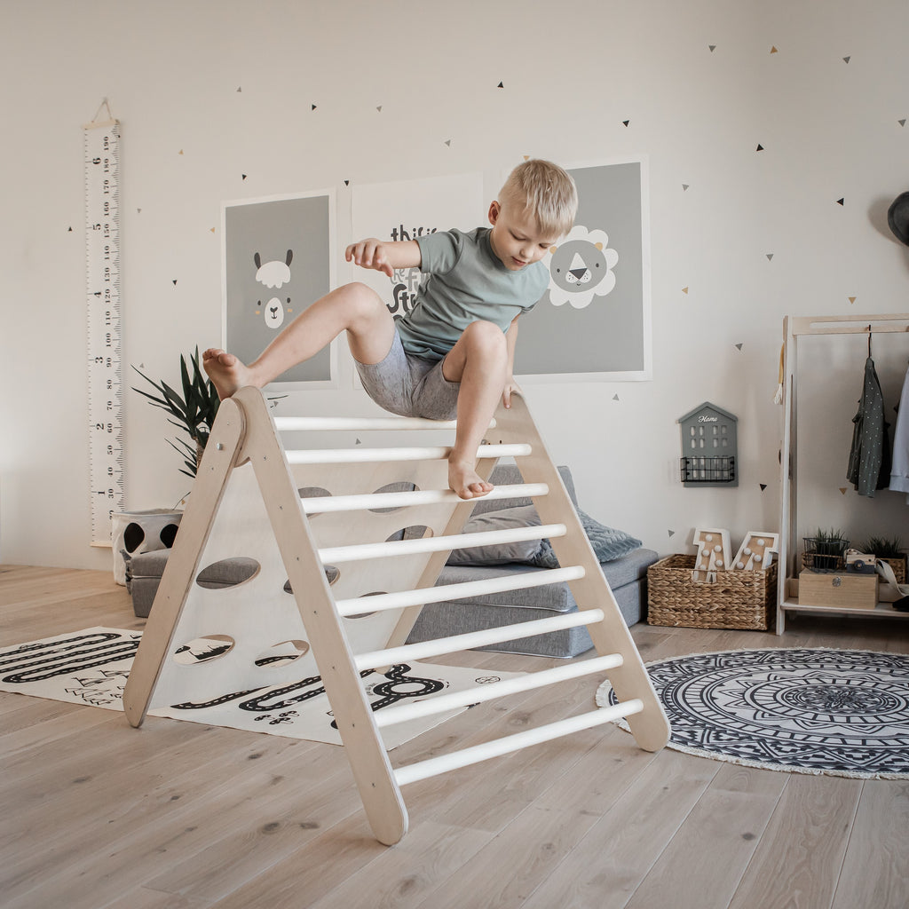 bold toddler climbing triangle in sunlight with confident child reaching top