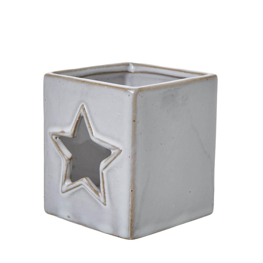White ceramic tealight holder with star cut-outs, casting delicate shadow patterns for home decor ambiance. by sostter at brixbailey.com
