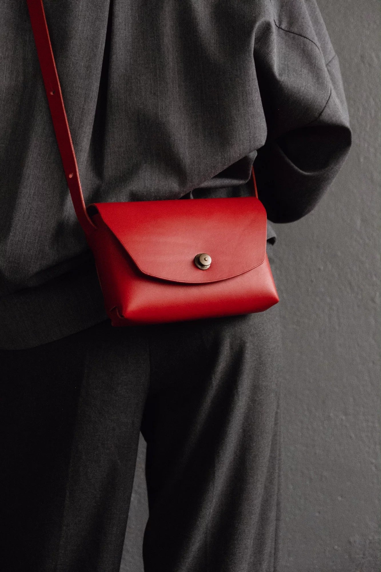 bold red italian leather clutch bag held confidently in hand against a dark urban backdrop