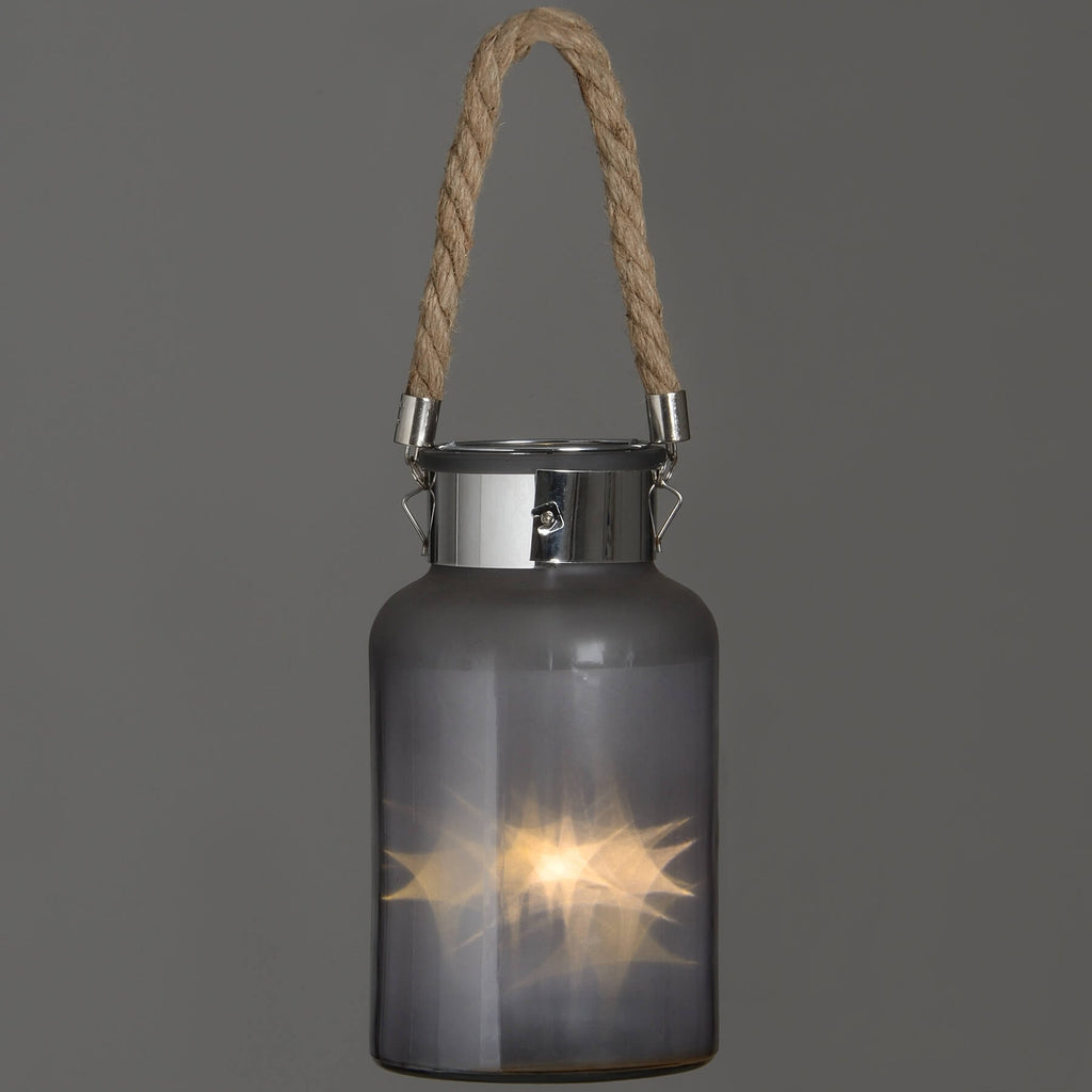 Frosted grey glass lantern with rope handle and warm LED glow, creating a starlight effect for indoor or outdoor decor. by RoomLondon at brixbailey.com