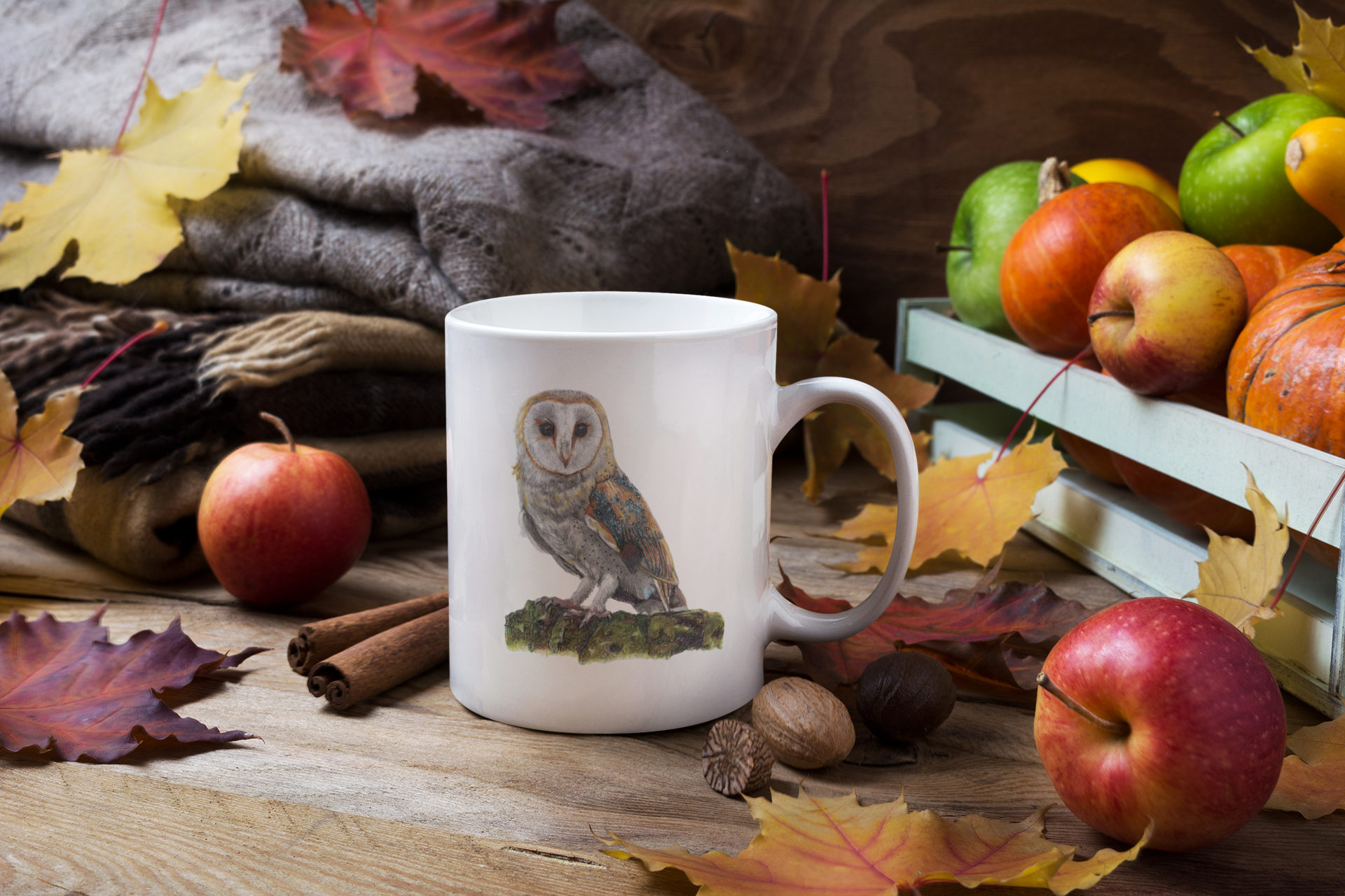 White mug with an owl design on a wooden surface with autumn leaves and fruits.