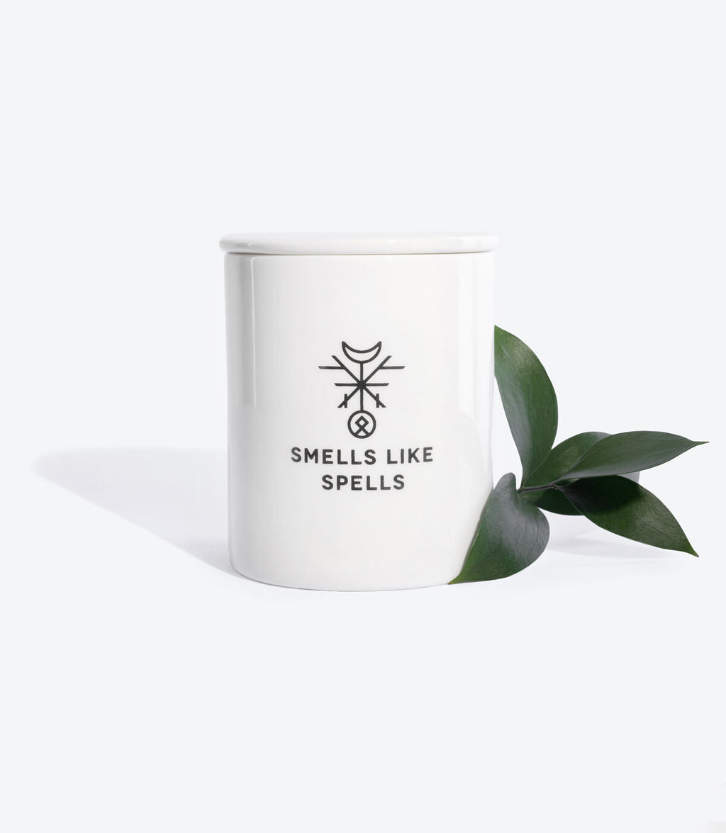 the chariot scented candle glowing boldly on a dark background, its porcelain vessel illuminated