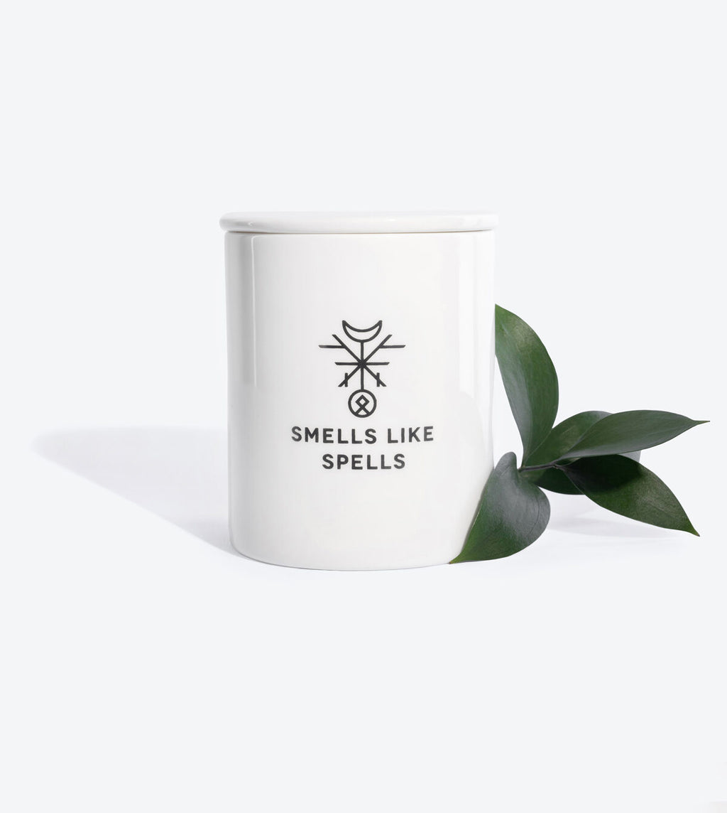 elegant handmade porcelain emperor tarot candle with cedar and saffron, glowing softly in refined light
