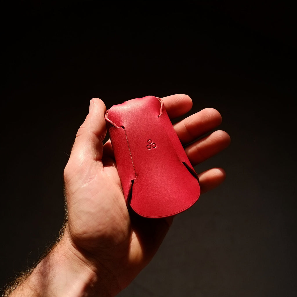bold red italian leather keyholder open on a dark background, showcasing its sleek folded design and premium craftsmanship