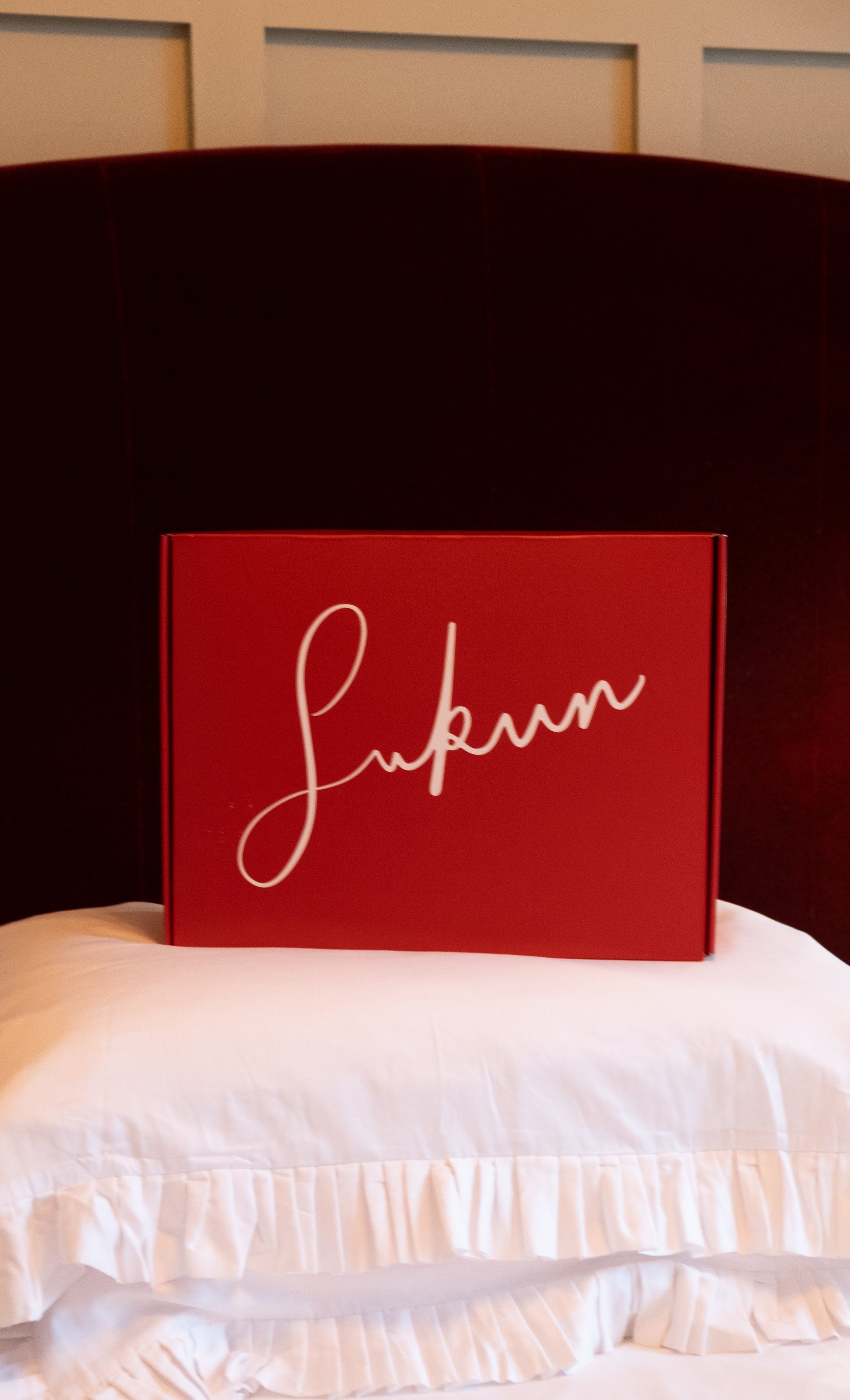 Red box with 'Sukun' branding on a white surface with a dark headboard. at Sostter