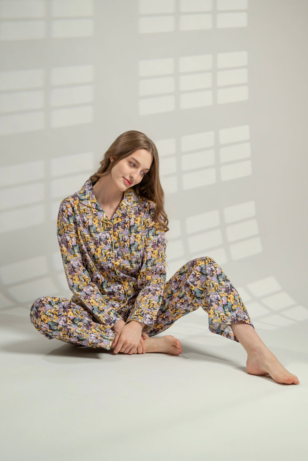 Woman wearing a floral pajama set sitting on a white floor.