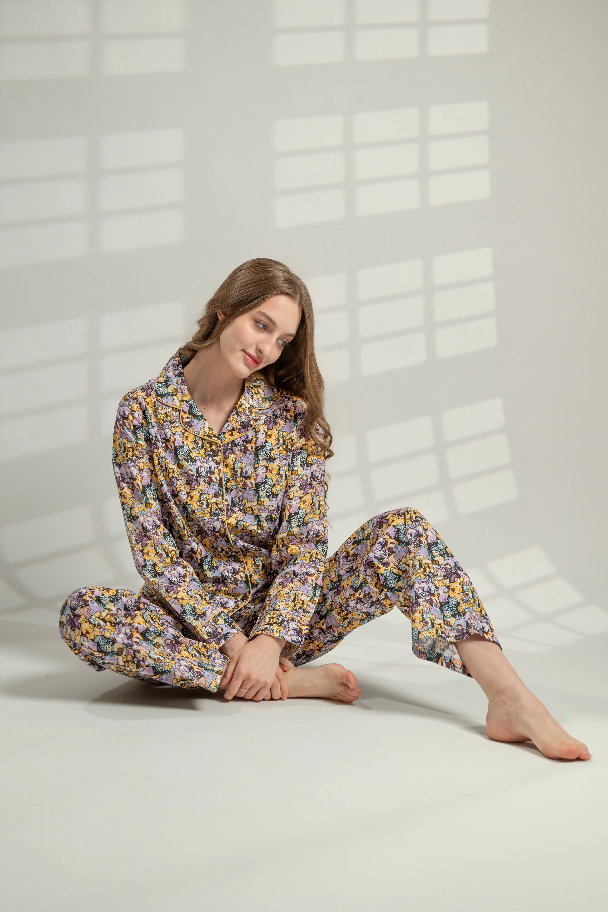 Woman wearing a floral pajama set sitting on a white floor.