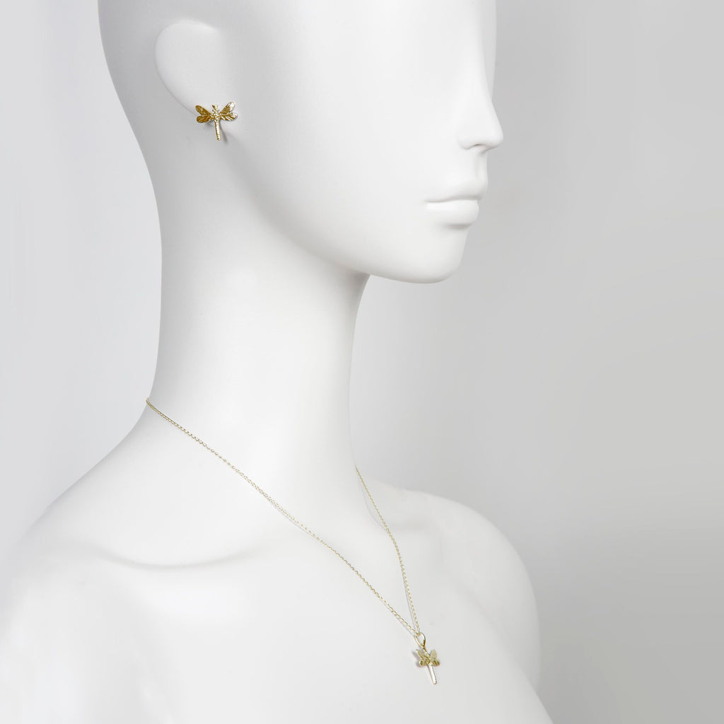 softly lit gold dragonfly earrings resting on a delicate surface, radiating a comforting and graceful glow