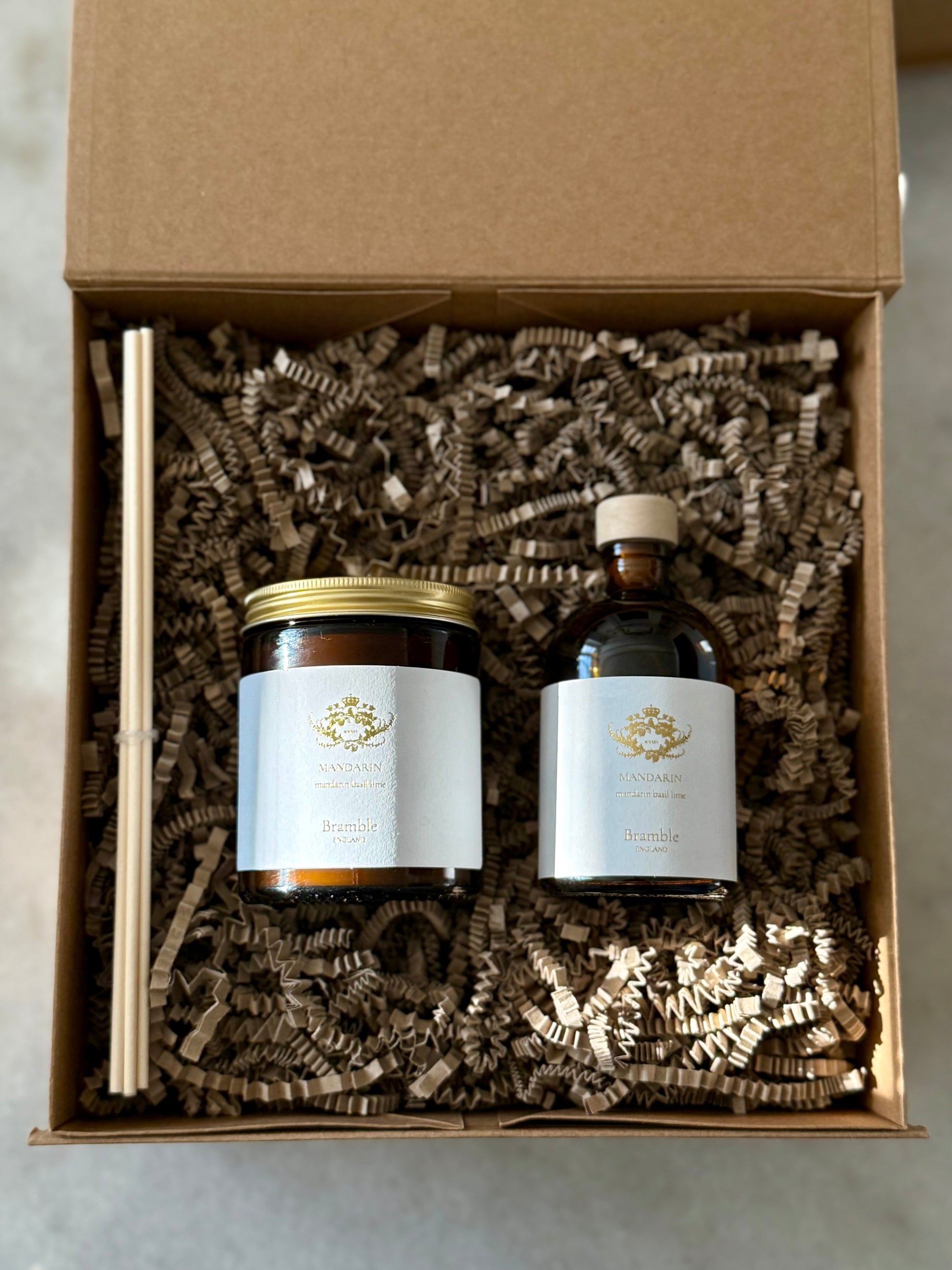 Two bottles with labels in a brown gift box with shredded paper