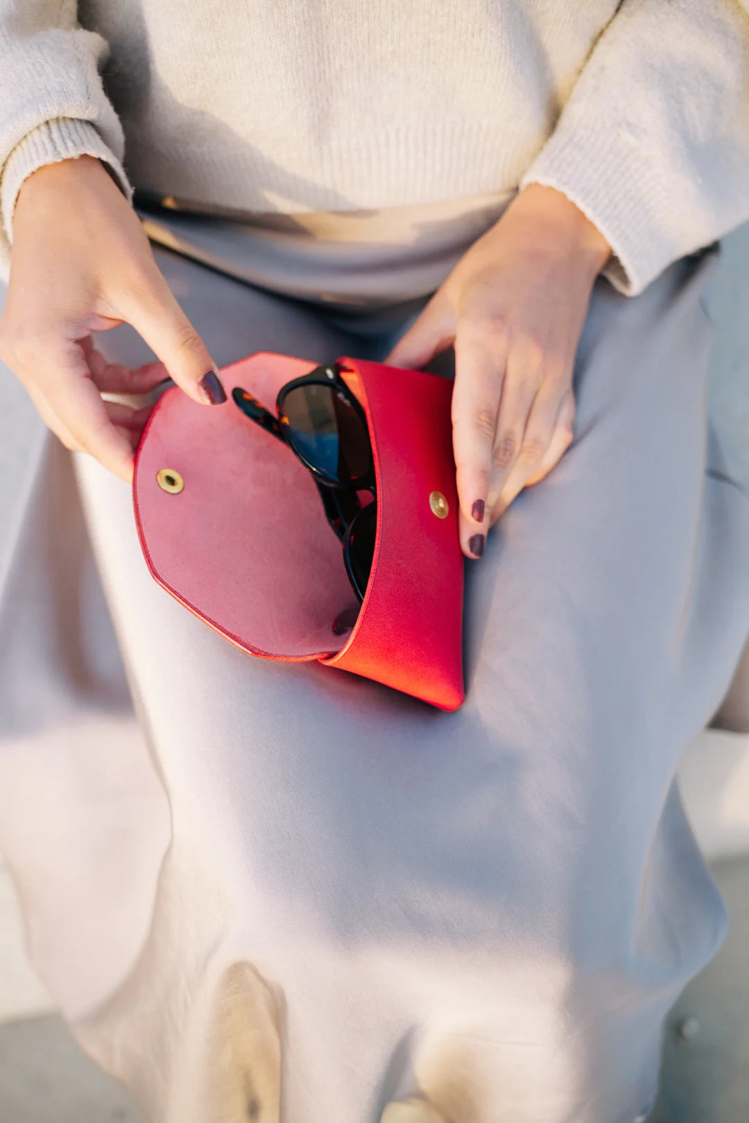 a playful red leather sunglasses case on a sunny windowsill, ready for an adventure
