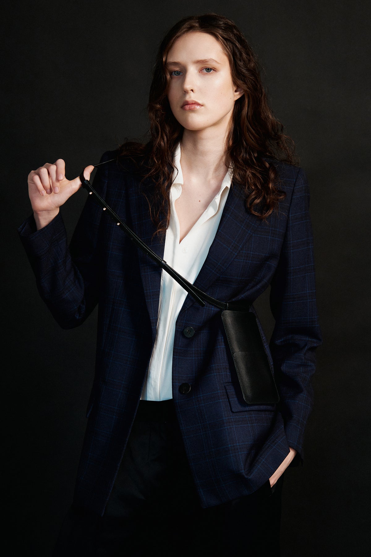 elegant black leather crossbody phone bag with gold sam browne buttons on an adjustable strap