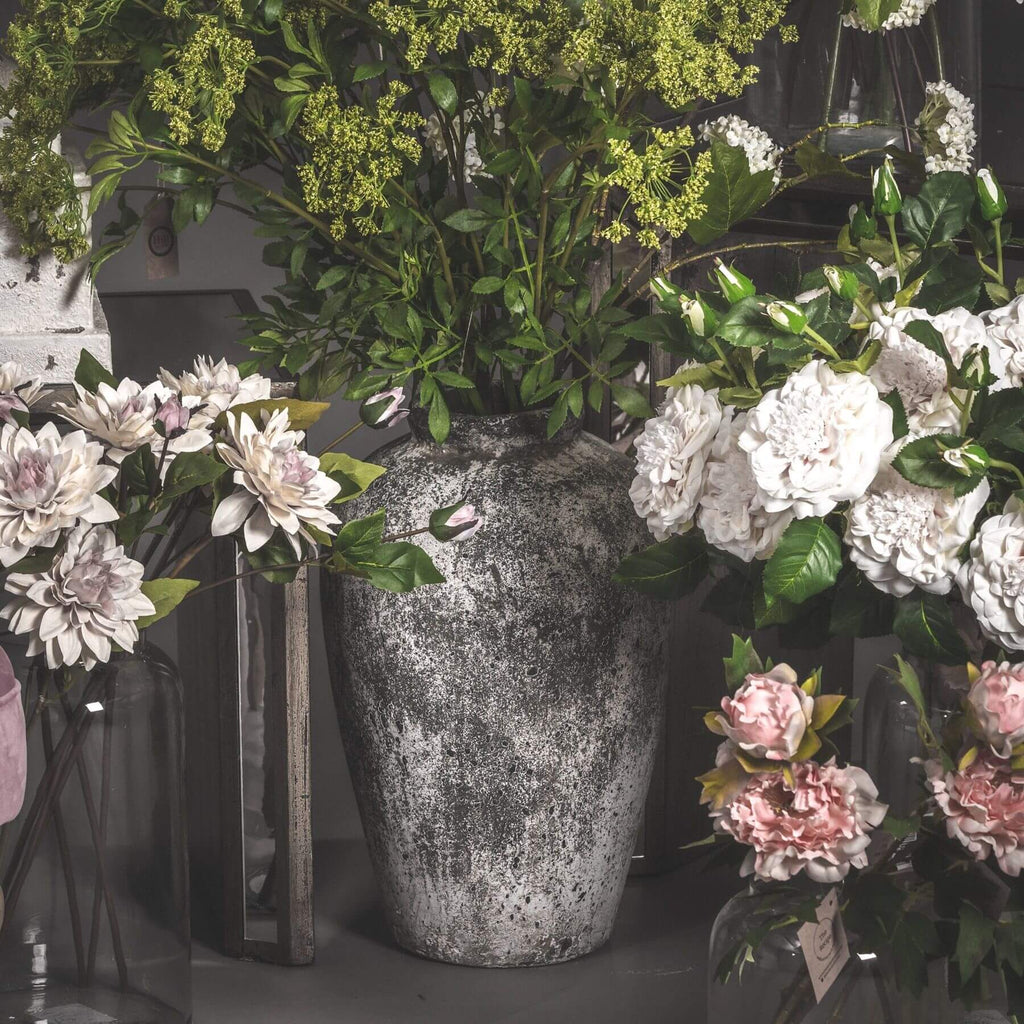 playful tall ceramic vase with a textured stone finish on a sunlit windowsill
