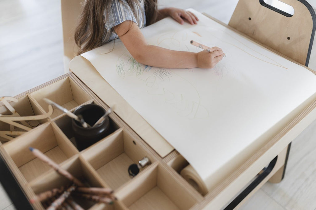 a soft pink kids table and chair set with a paper roll and hidden storage for art supplies