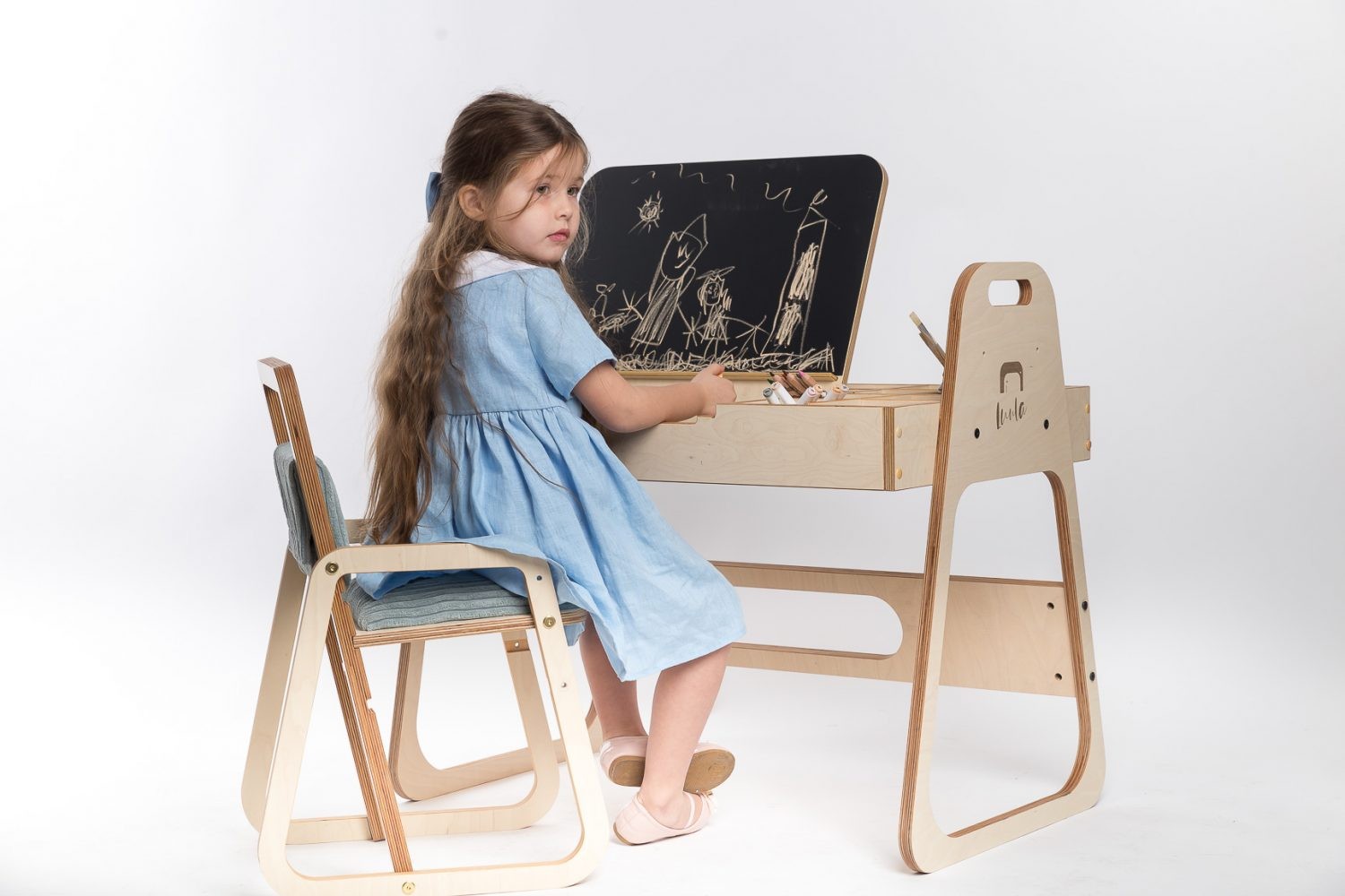 mint green kids art table with chalkboard and paper roll in a bright, sunlit playroom