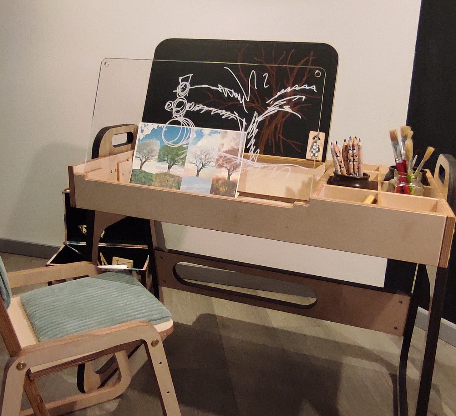 mint green kids art table with chalkboard and paper roll in a bright, sunlit playroom