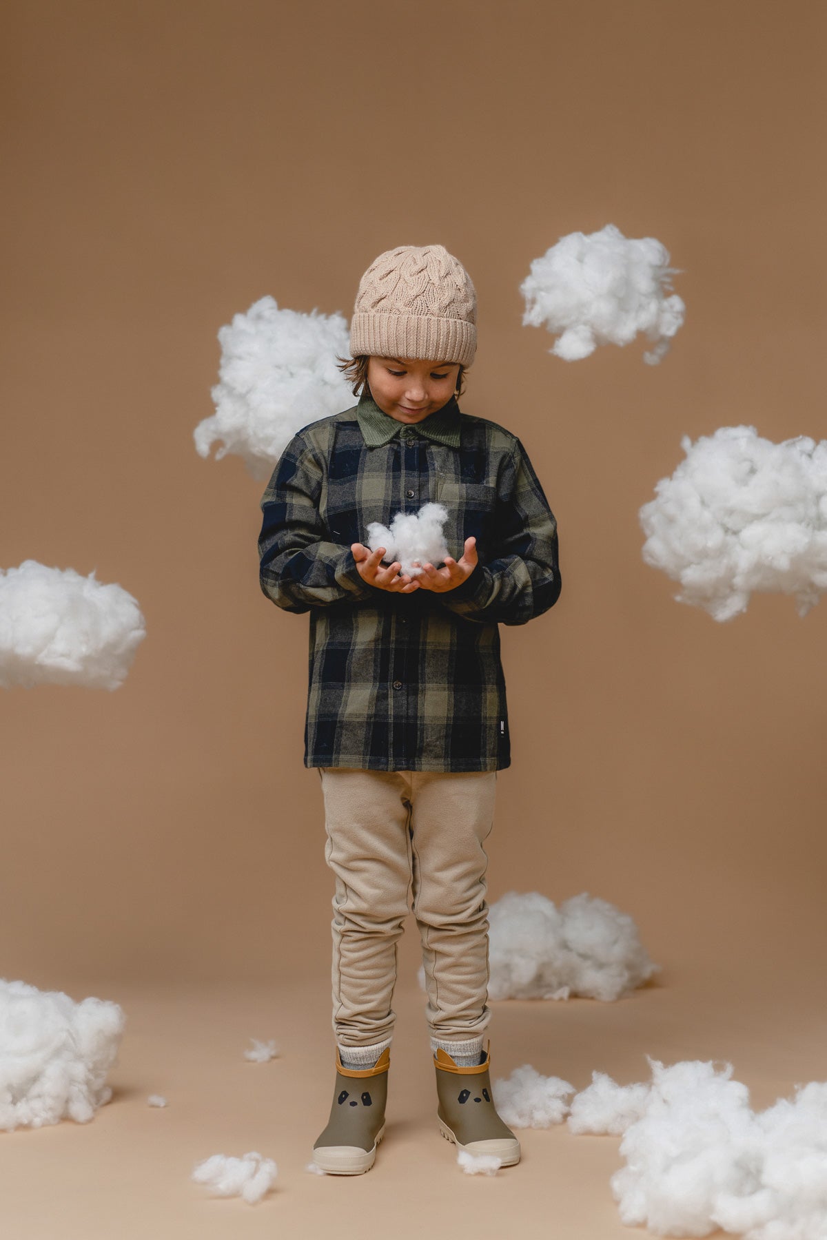 playful wheat-colored alpaca cable hat with a fluffy pompom on a child laughing outdoors