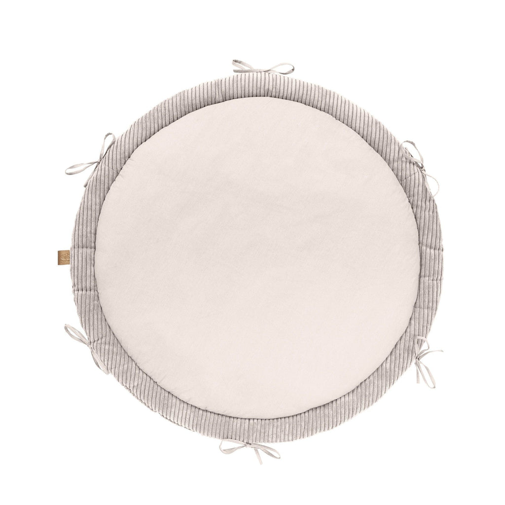 a playful baby enjoying tummy time on a soft vanilla nest with a cozy braided bumper
