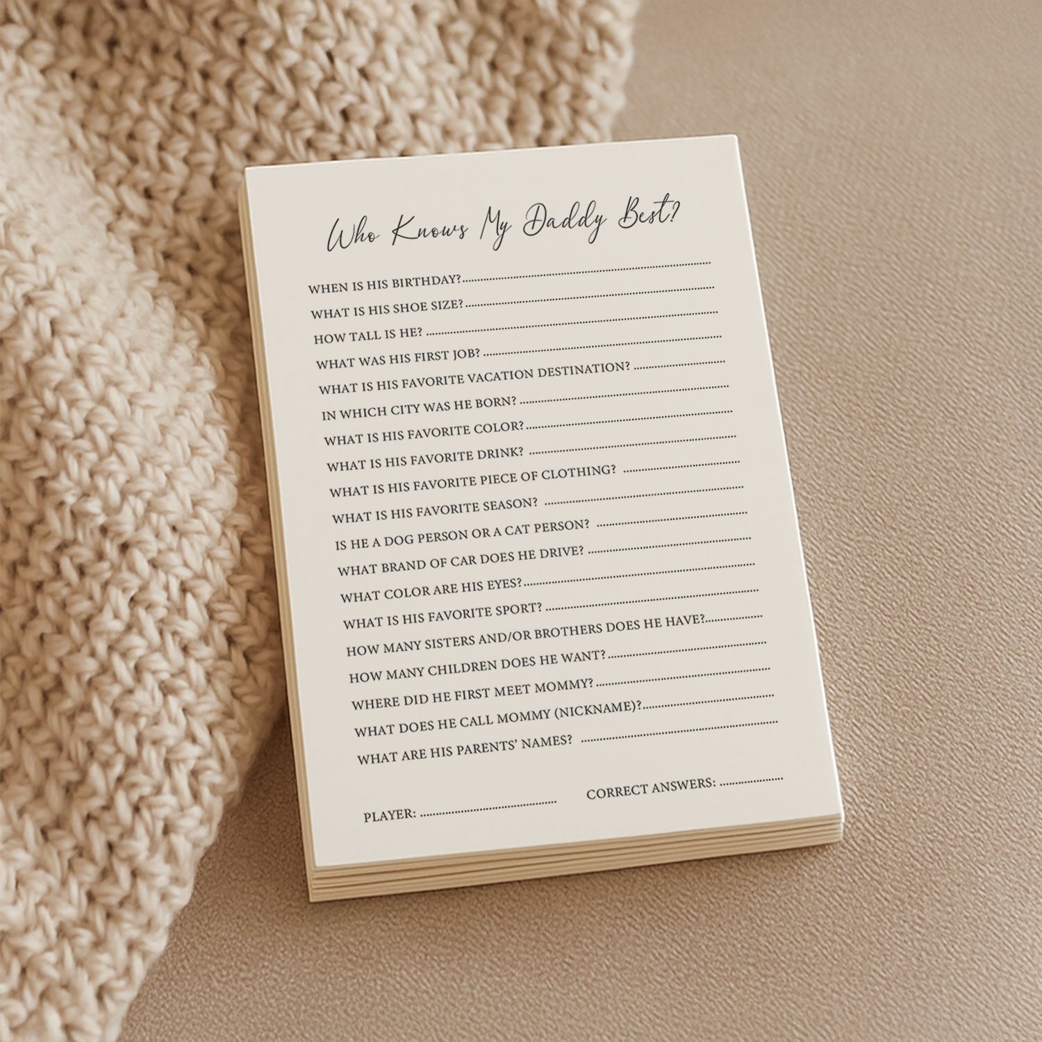 a soft-lit close-up of the who knows daddy best game cards on a cozy knitted blanket
