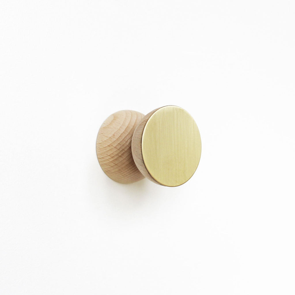 close-up of a beech wood and brass wall hook with screw and bolt for practical installation