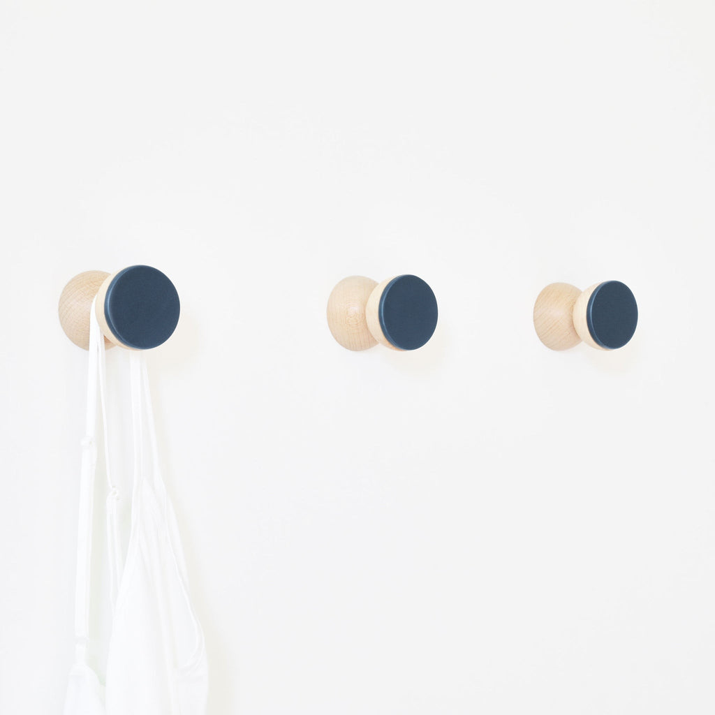 bold dark blue ceramic wall hook on a minimalist concrete background