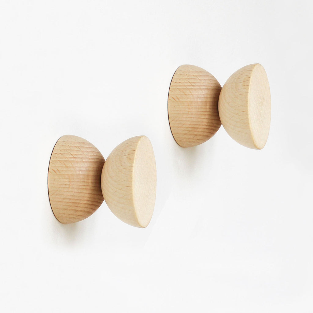 a single beech wood wall hook in warm morning light on a clean white wall
