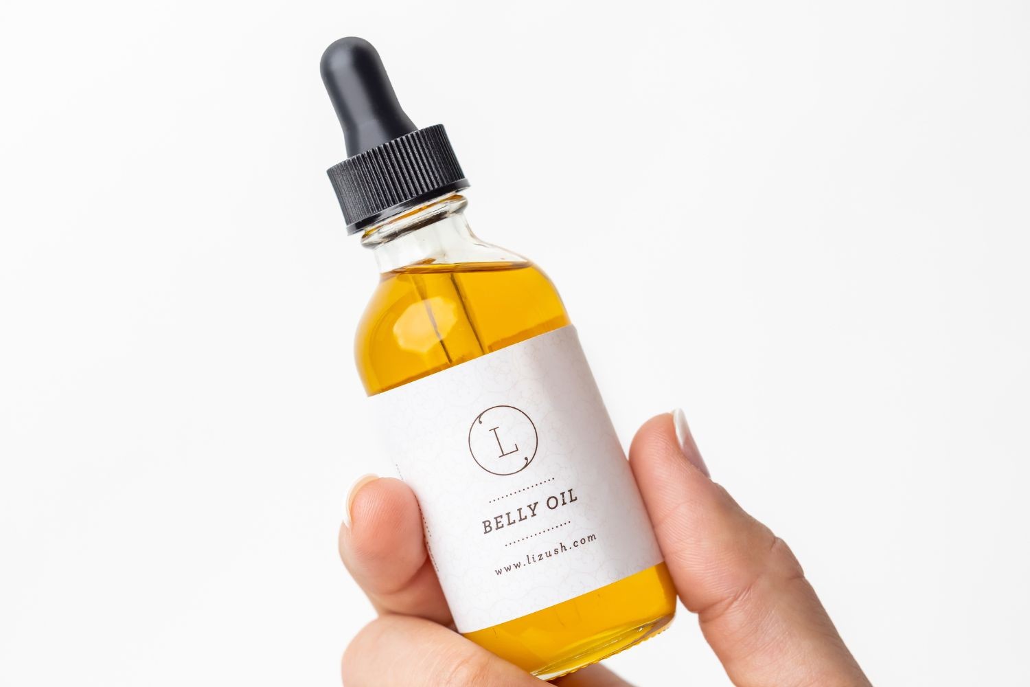 practical close-up of natural stretch mark oil being applied to a pregnant belly