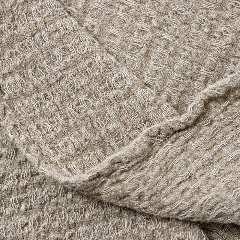 textured grey linen bath towel draped elegantly over a dark wood rail