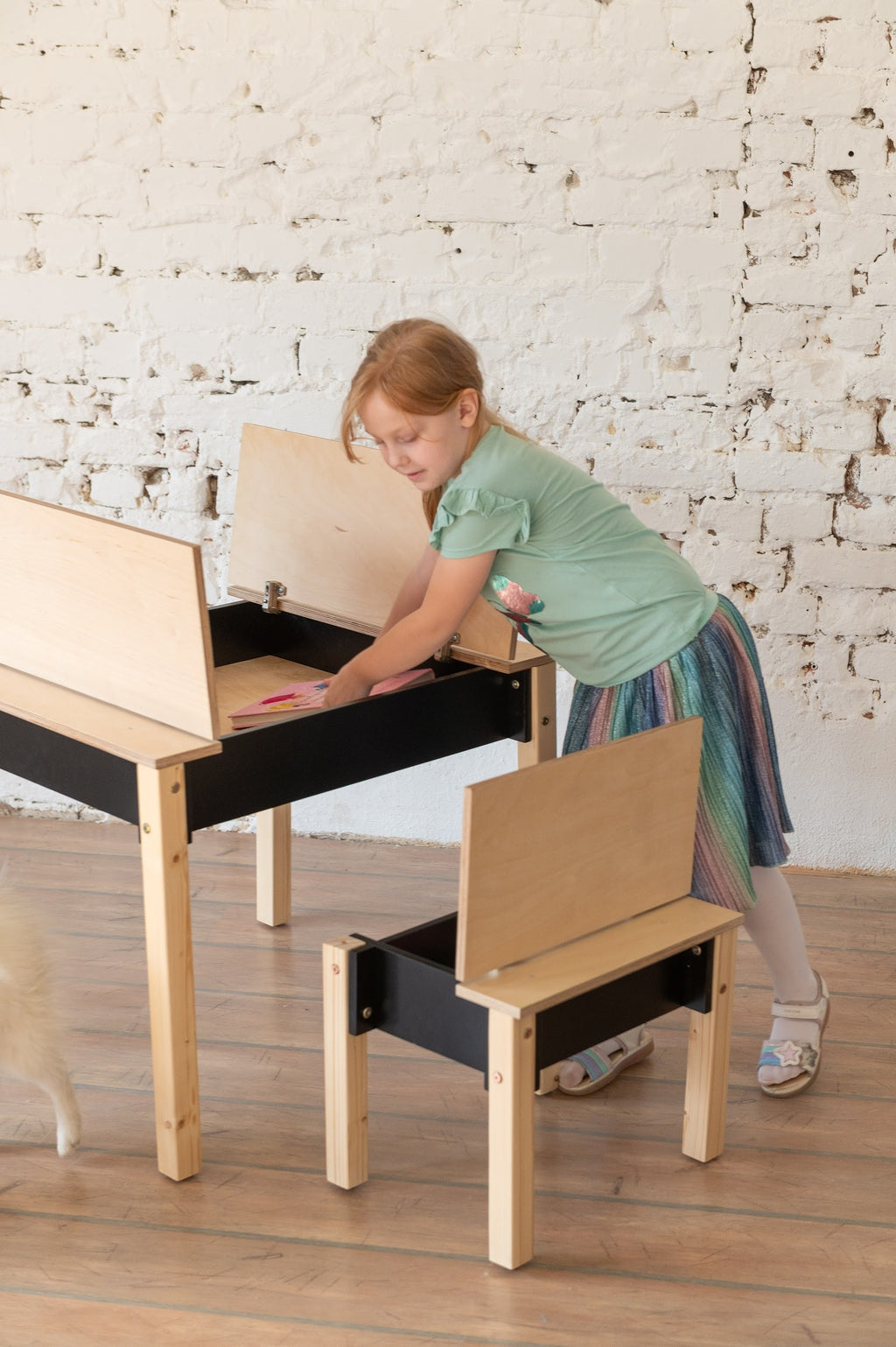 a playful toddler pulling a book from the secret storage compartment of their birch wood chair