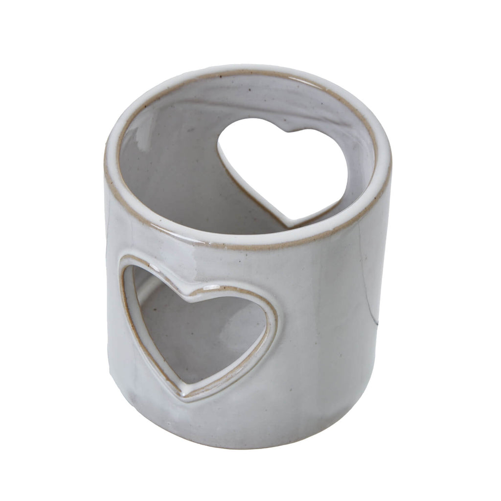 White ceramic tealight holder with heart cutouts, casting romantic shadow patterns for cozy ambiance. by RoomLondon at brixbailey.com