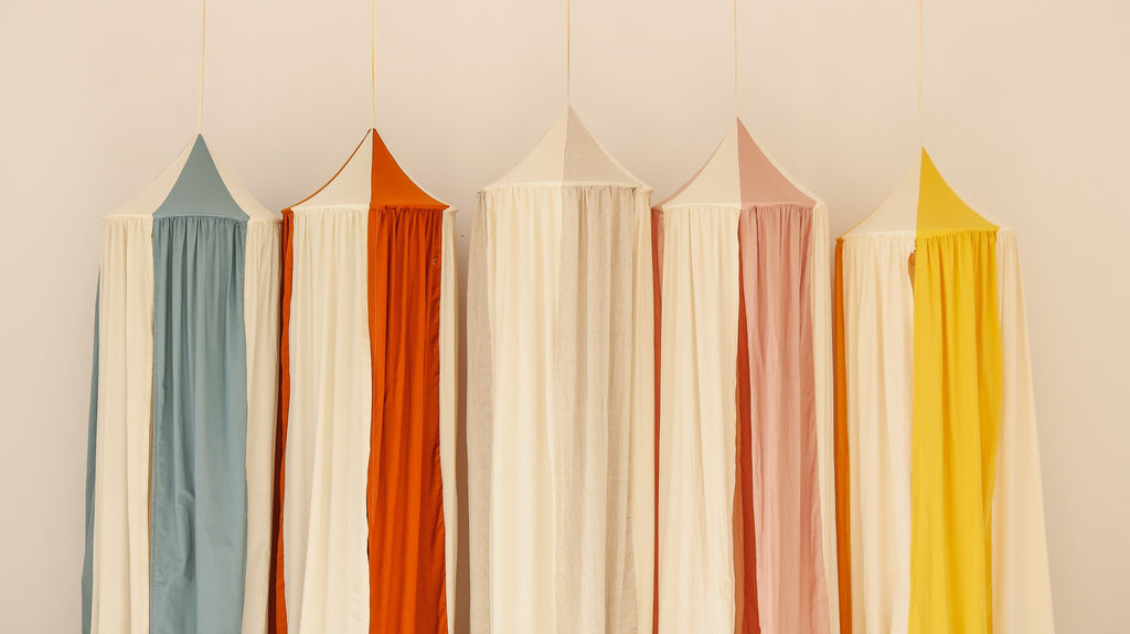 a playful blue circus canopy hung over a child's bed with soft toys peeking out from underneath