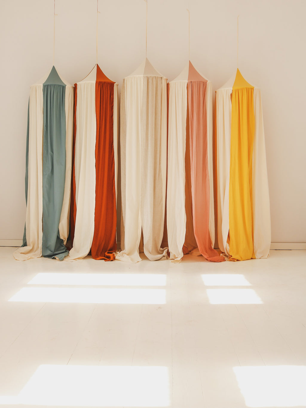 blue circus canopy hung over a child's bed with soft morning light filtering through the organic linen