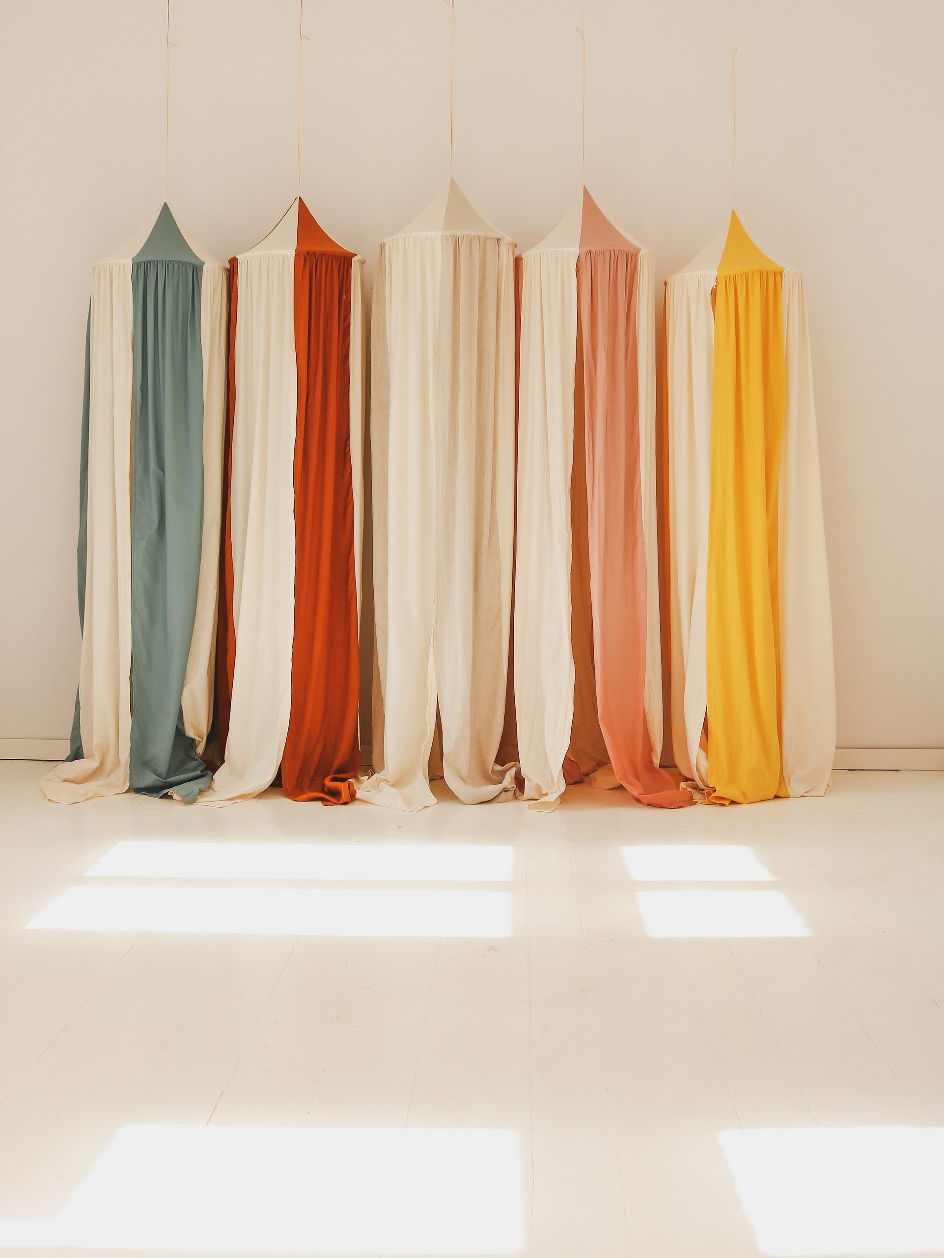 blue circus canopy hung over a child's bed with soft morning light filtering through the organic linen