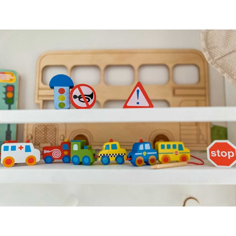 confident child threading vibrant wooden car blocks on a bold red string