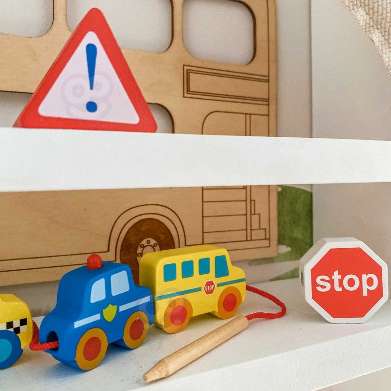 child's hands threading a wooden fire truck block onto a string