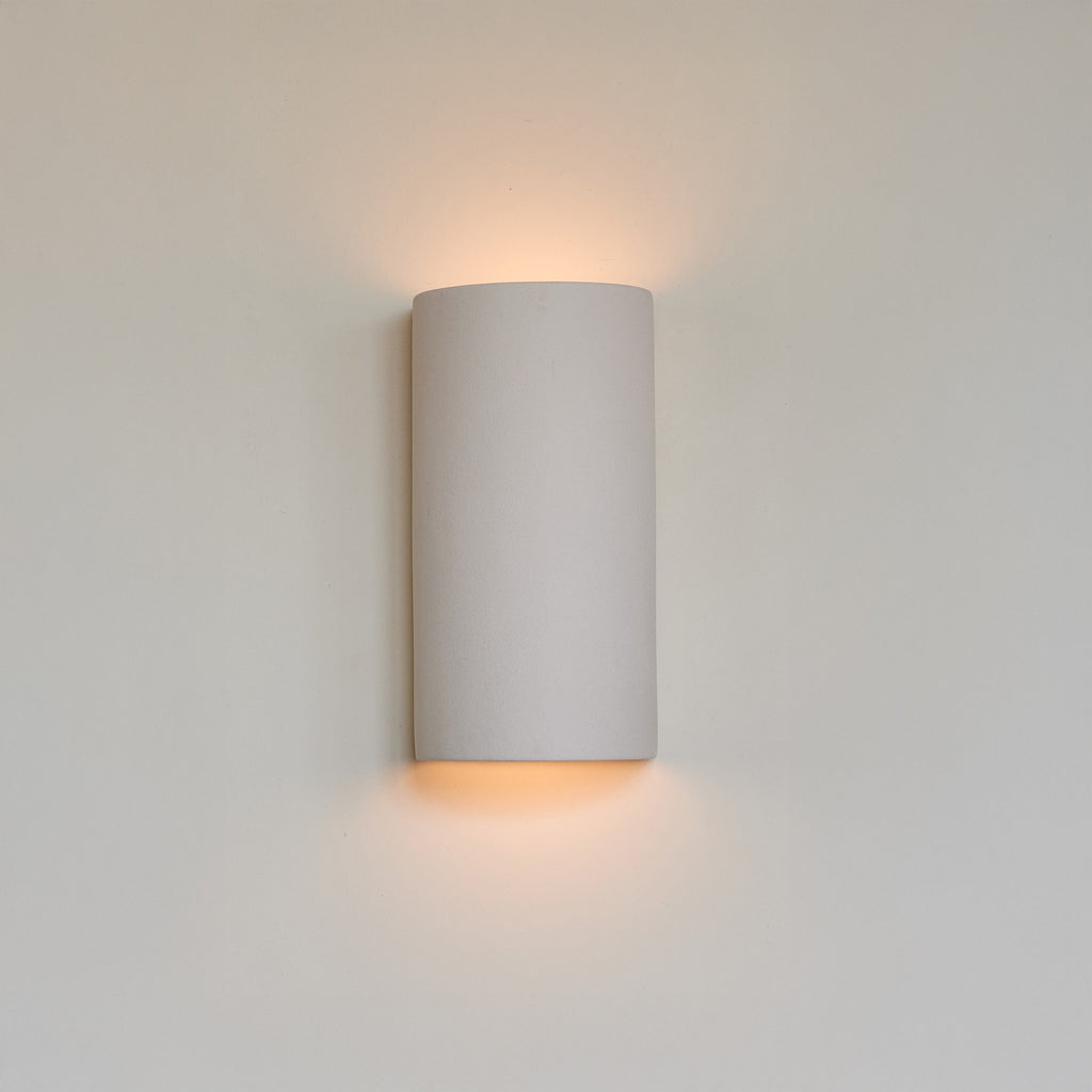 bold matte white ceramic wall sconce casting a dramatic sculptural shadow