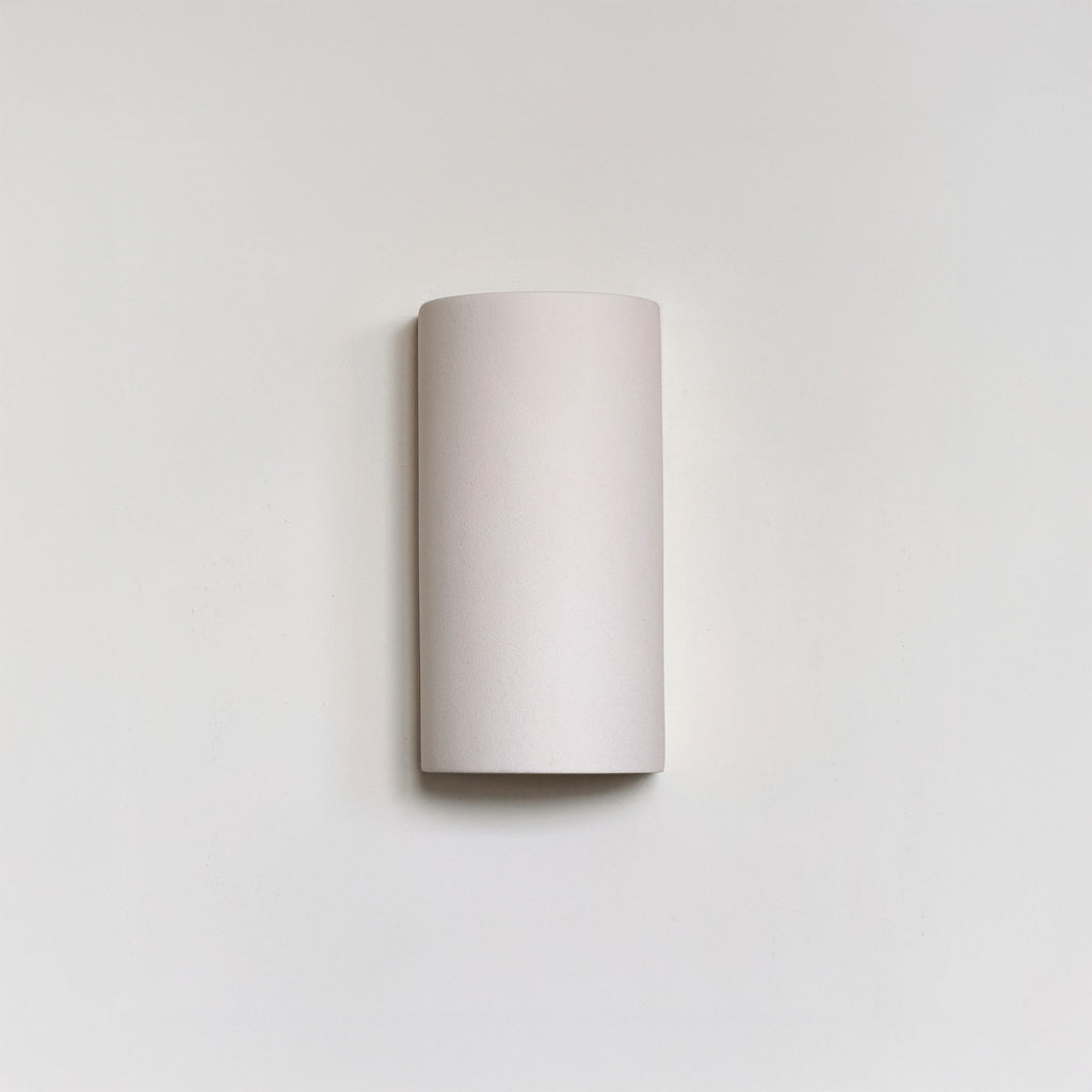 a playful white ceramic wall light casting a fun, patterned shadow on a nursery wall
