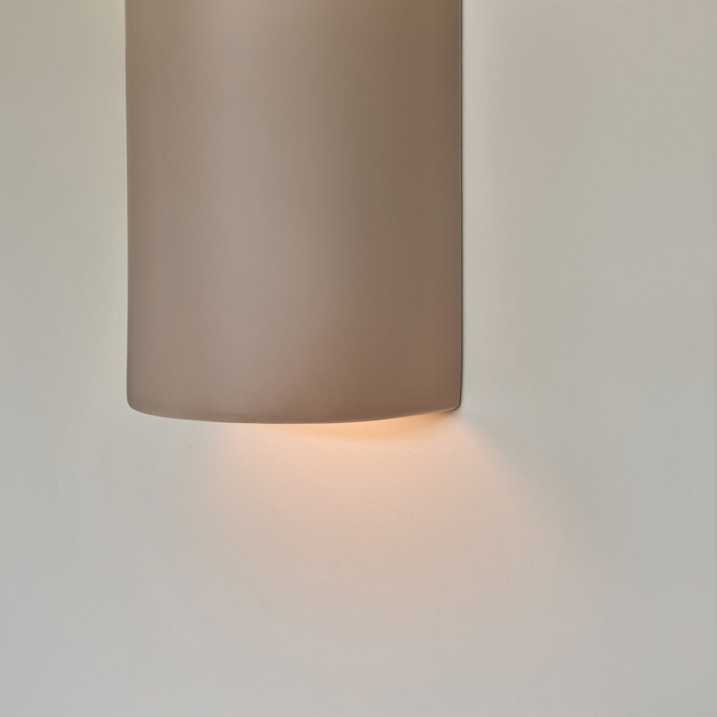a playful taupe ceramic wall light casting a fun, whimsical shadow on a nursery wall