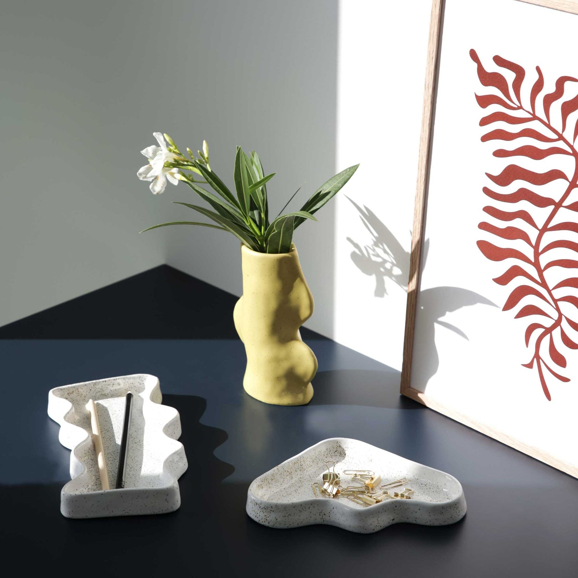playful speckled ceramic wave tray holding colorful jewelry on a sunny bathroom counter