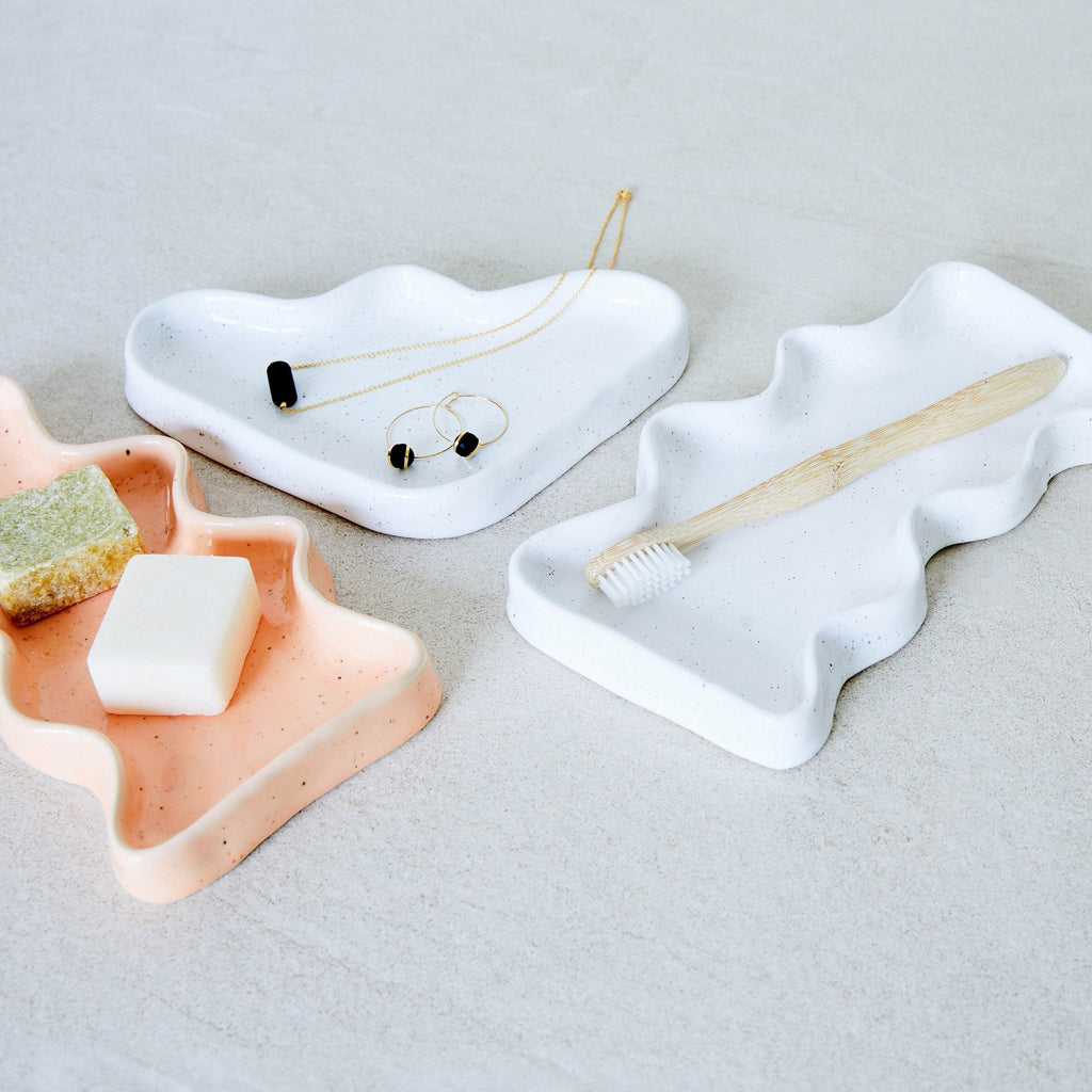 elegant white ceramic wave tray with speckled glaze, displayed on a marble surface under soft lighting