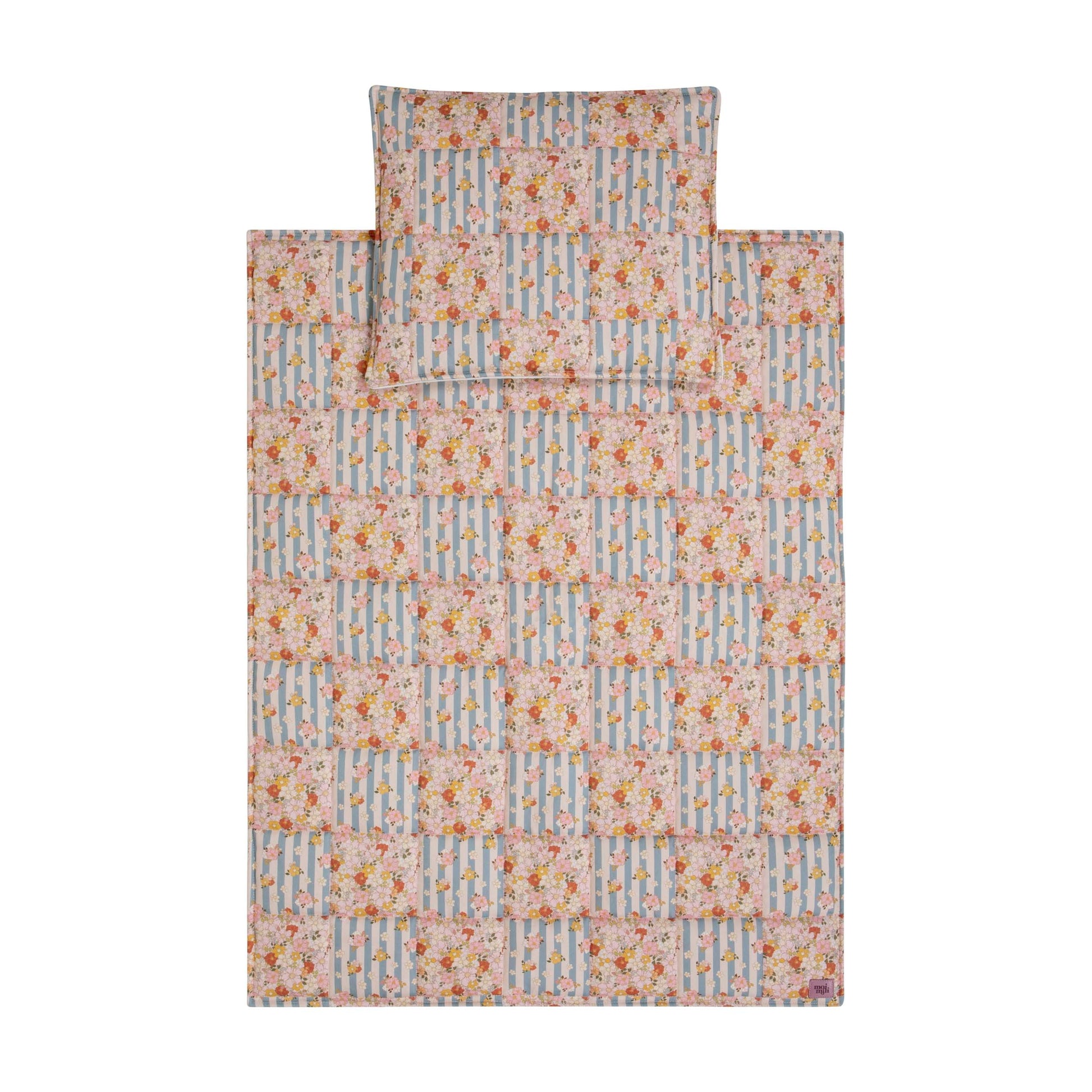 soft cotton quilted patchwork blanket and pillow set in summer garden print, laid out on a wooden floor with natural sunlight