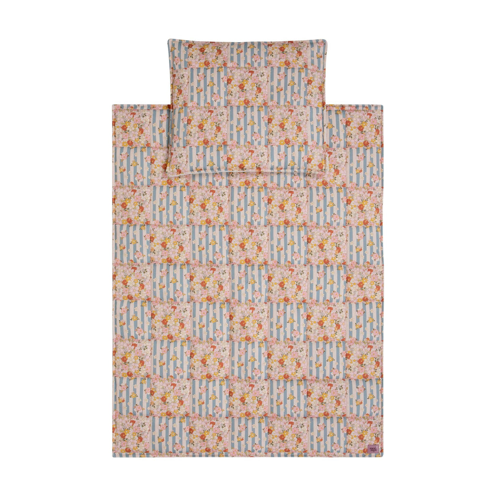 elegant summer garden quilted blanket and pillow set with delicate patchwork on a neutral linen backdrop