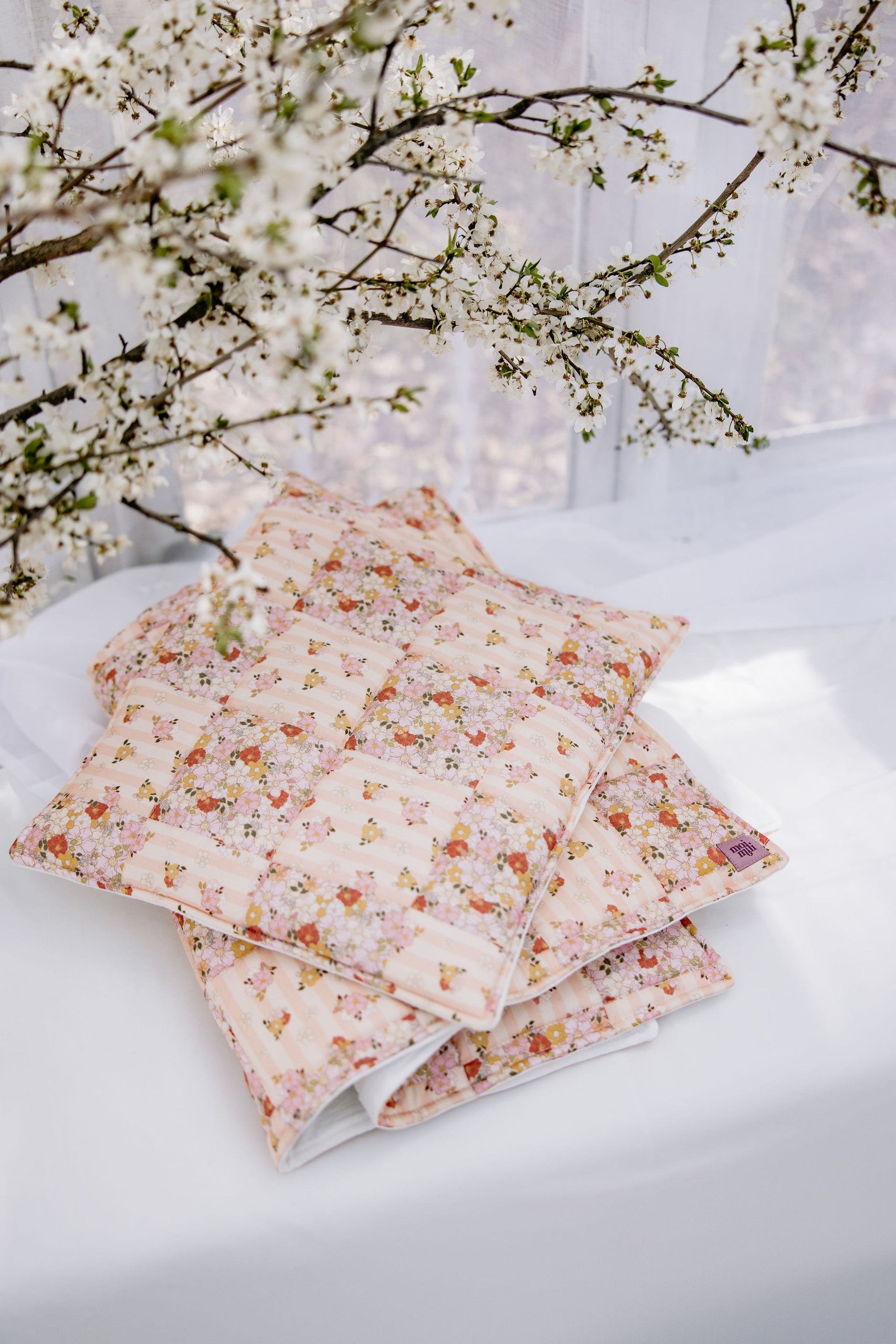 playful spring garden quilted blanket and pillow set laid on grass, vibrant patchwork patterns under sunlight