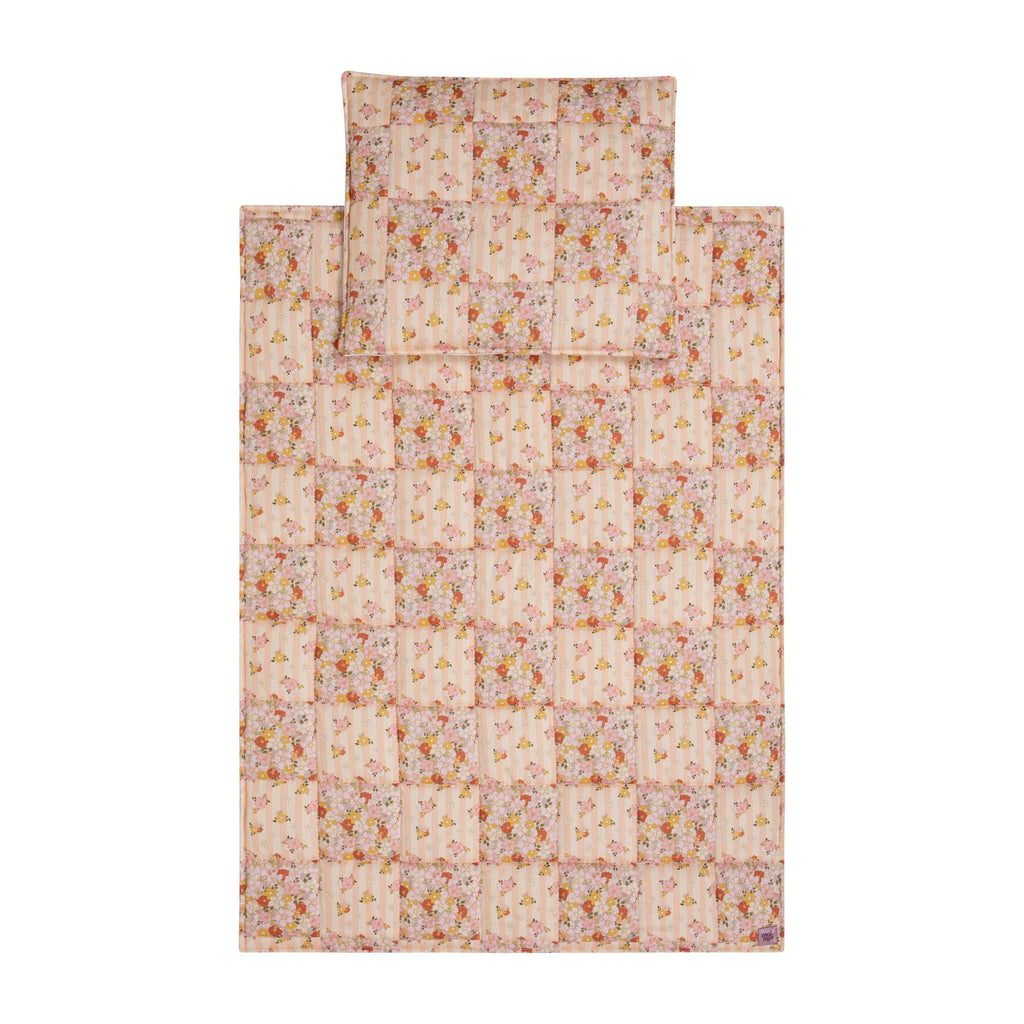 soft cotton quilted blanket and pillow set in spring garden print, draped gently over a wooden rocking chair