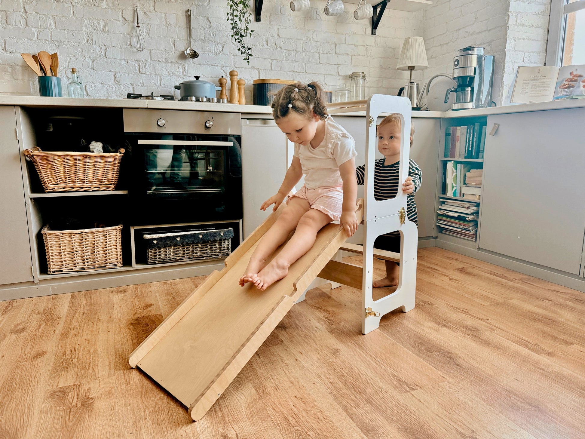 confident toddler stands at the blackboard of a sturdy 4-in-1 learning tower, ready to create