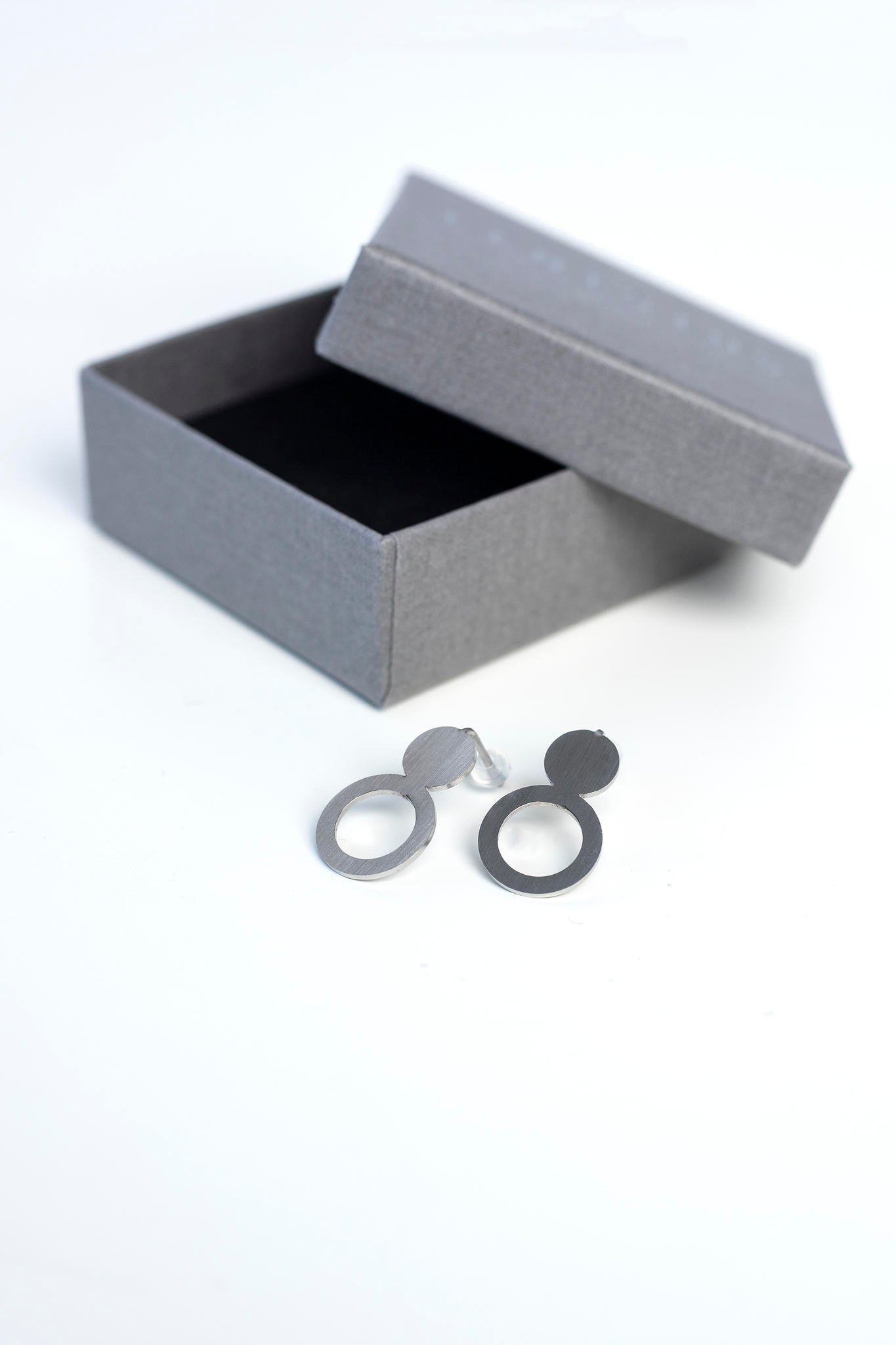 a playful close-up of silver arc earrings catching the light with a cheeky wink