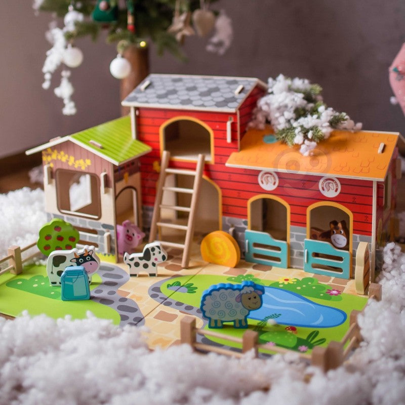a child's hand playfully arranging the woopie green farm animals near the wooden barn