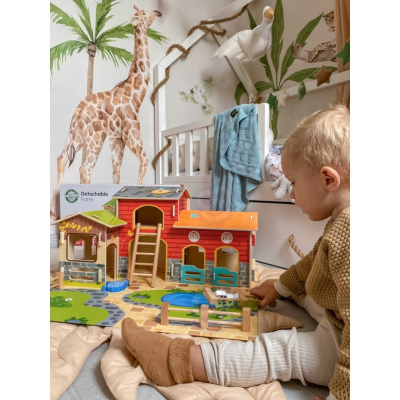 a child's hand arranging the woopie green farm set animals in the hay
