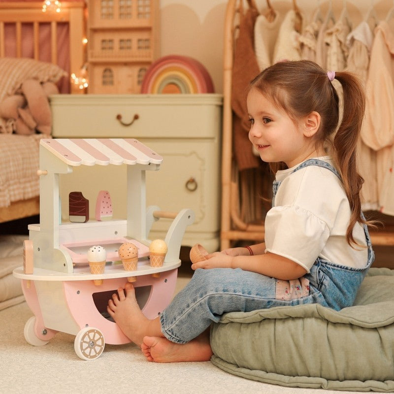 a child's hands arranging the magnetic ice cream scoops on the pastel green cart